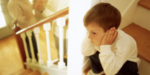 Boy on stairs listening to parents fighting